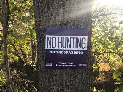 Purple No Hunting Sign on tree, woods